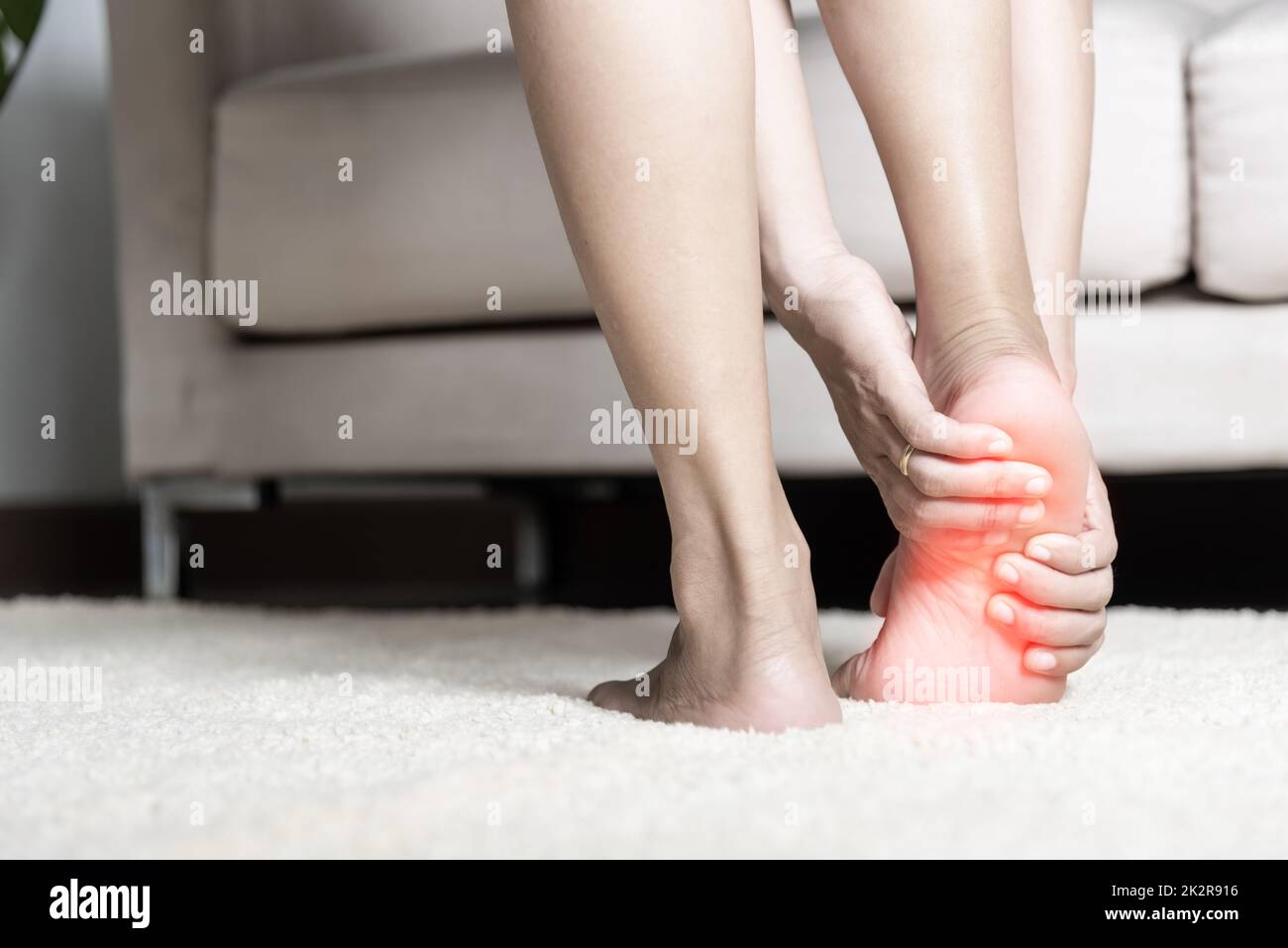 Foot pain, Asian woman standing feeling pain in her foot at home