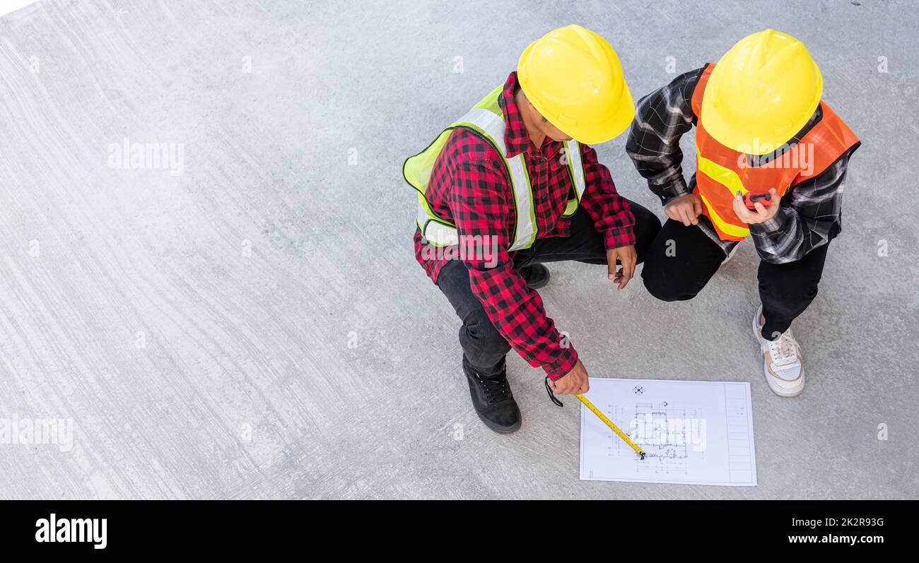 Architect and client discuss help create plan with blueprint of the building at construction site floor Stock Photo