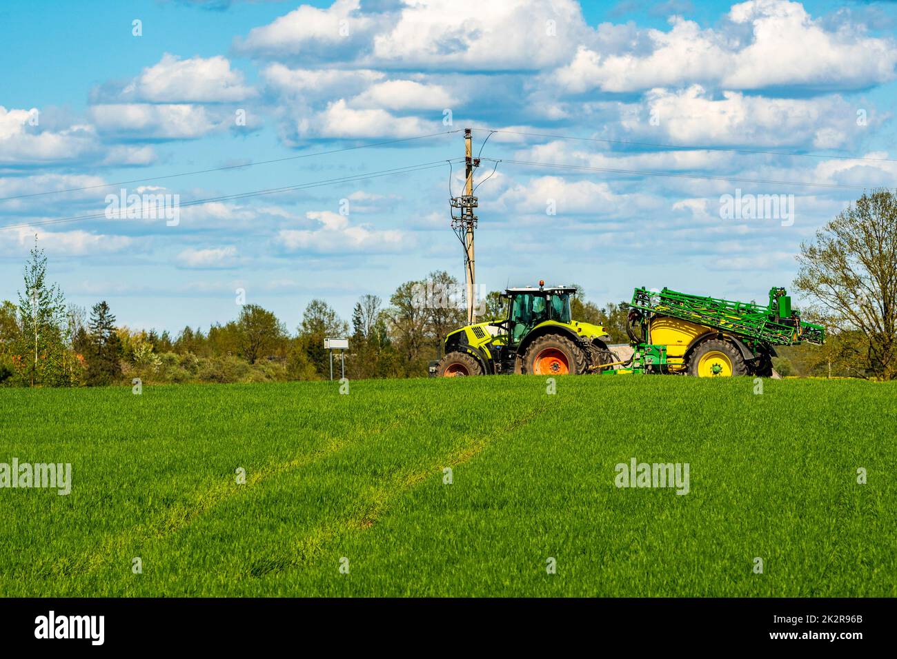 Tractor with sprayer going over green field Stock Photo