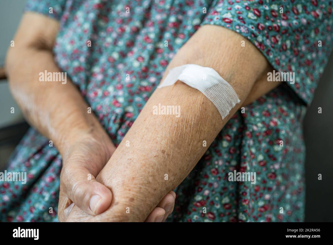 Asian senior or elderly old lady woman patient show cotton wool stop bleeding, after blood drawing testing for annually physical health check up to check cholesterol, blood pressure, and sugar level. Stock Photo