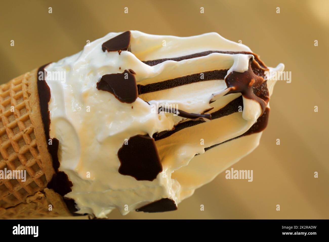 A close-up of a delicious ice cream cone with waffle, vanilla ice cream and chocolate icing. Stock Photo