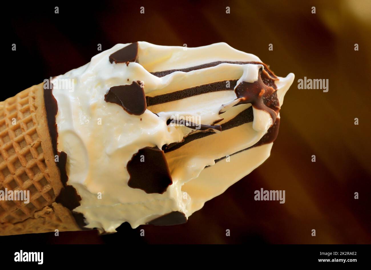 A close-up of a delicious ice cream cone with waffle, vanilla ice cream and chocolate icing. Stock Photo