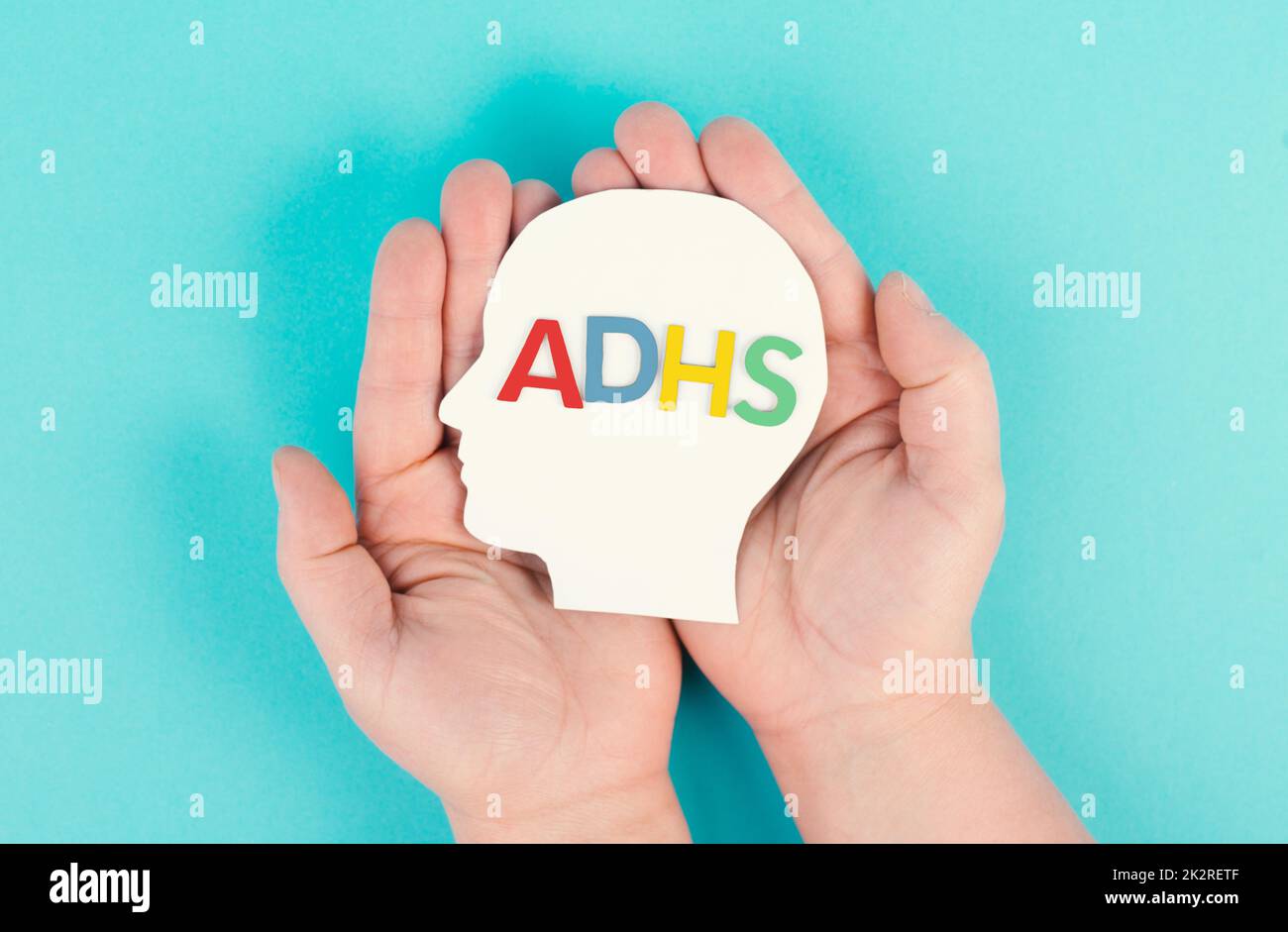 Hands holding a head with the german word ADHS which means attention
