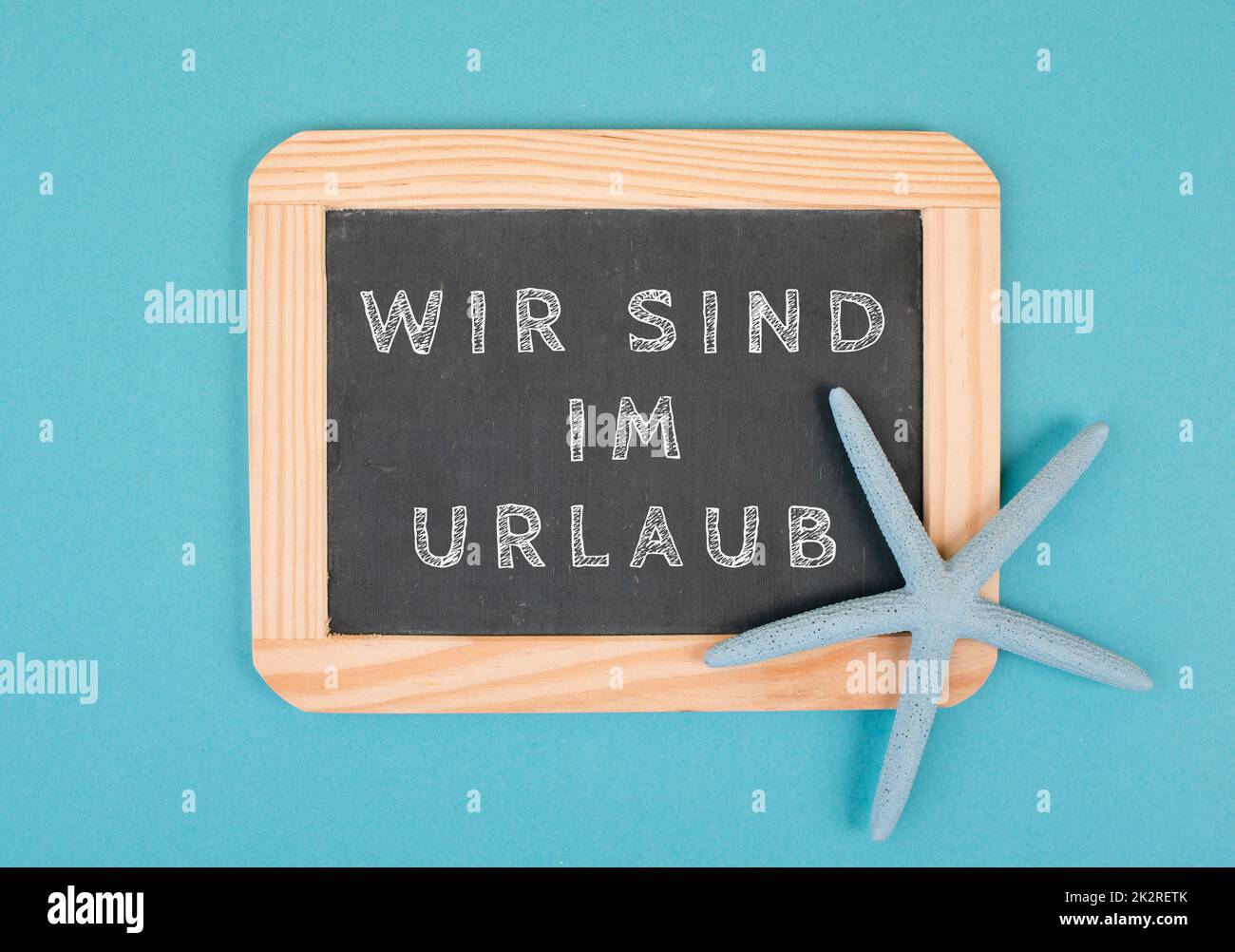 We are on vacation is standing in german language on the chalkboard with a sea star, holiday background, time out in summer, hot weather, advertising and marketing concept Stock Photo