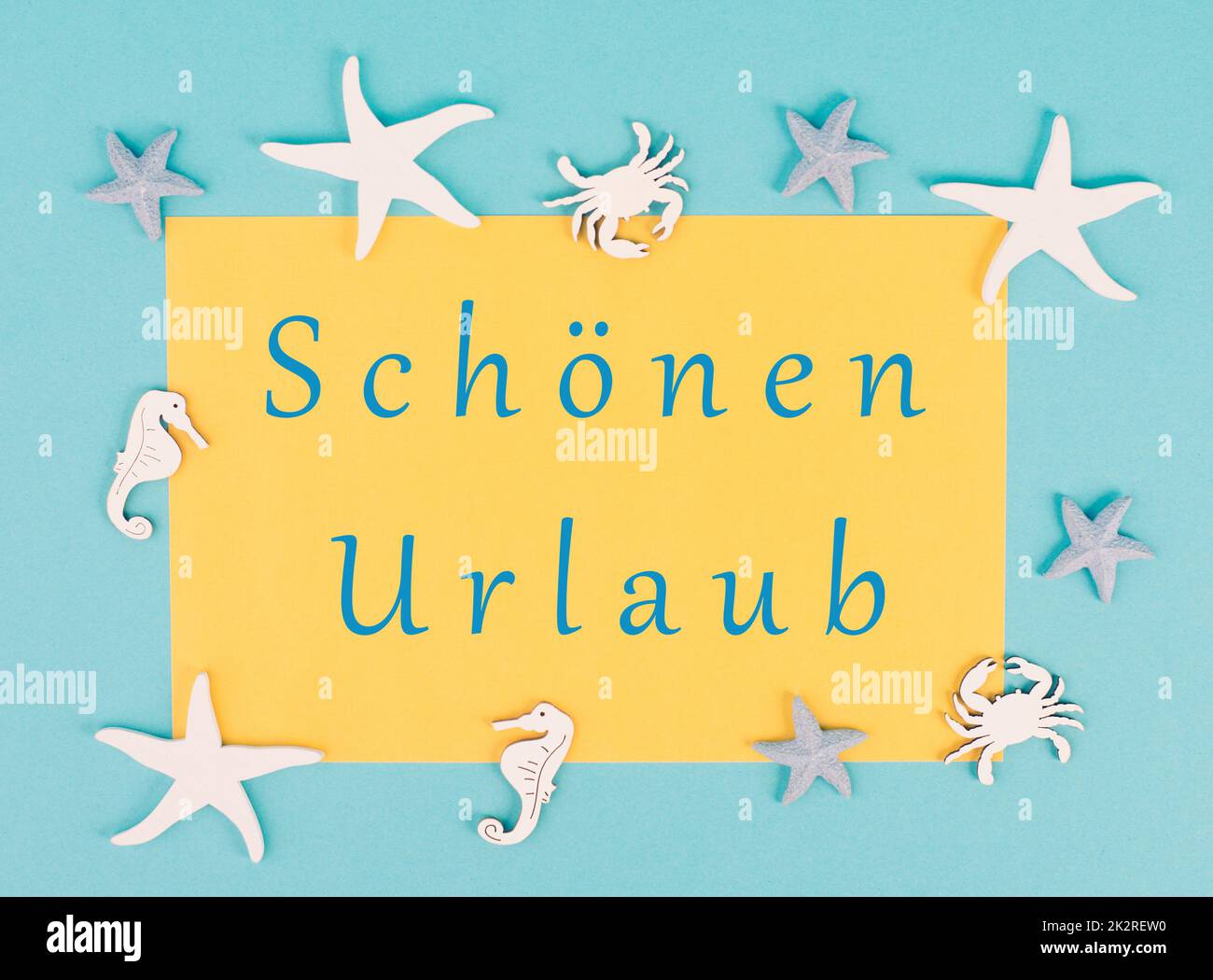 Yellow colored paper with the words nice vacation in german language, sea stars, seahorses and crab bulding a frame, summer holiday, tourism travel destination Stock Photo
