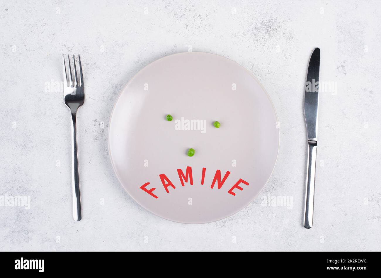 Famine is standing in german language on the plate, food shortage and starving because of the war and inflation, political issue Stock Photo