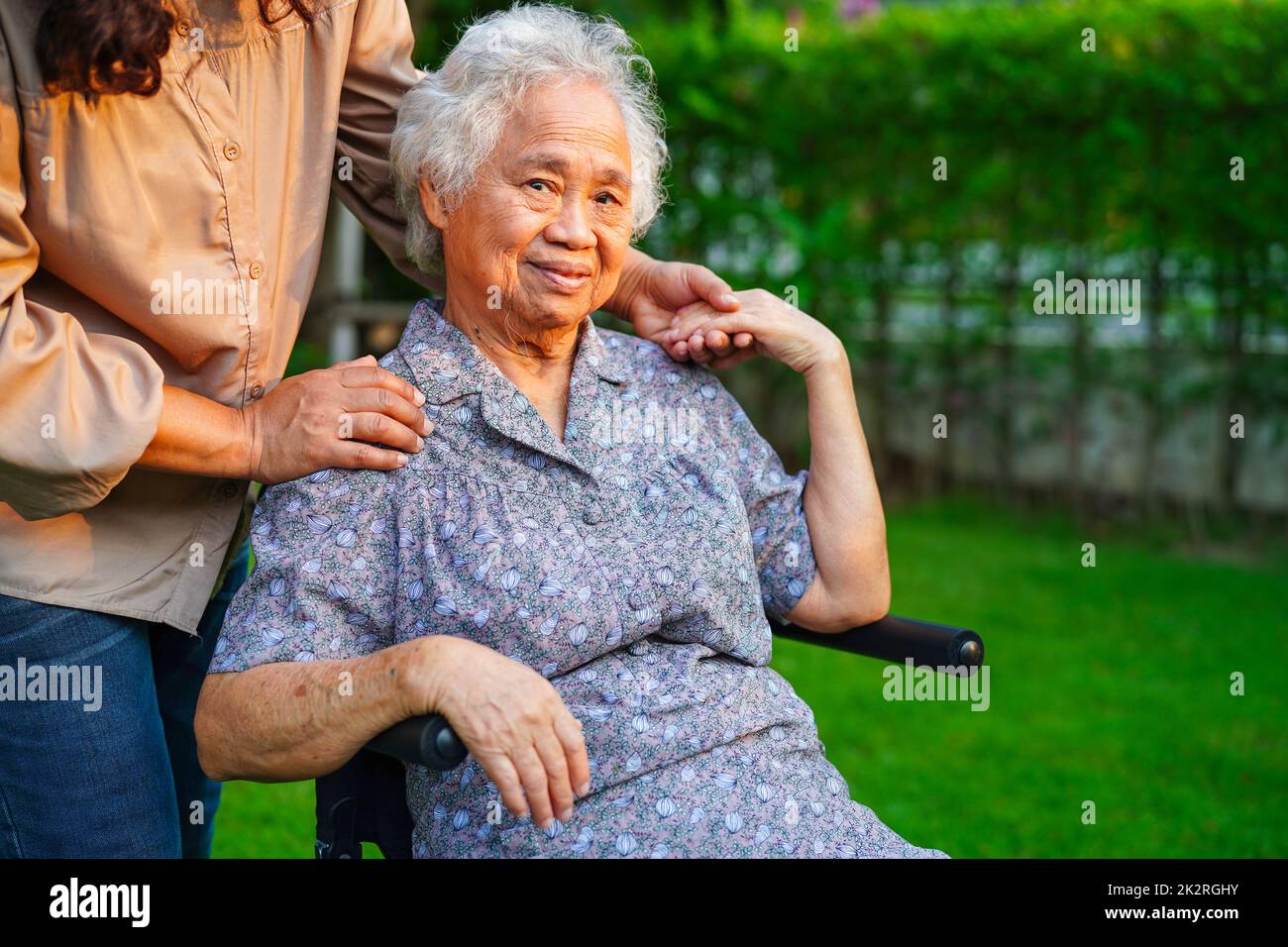 Caregiver help Asian elderly woman disability patient sitting on