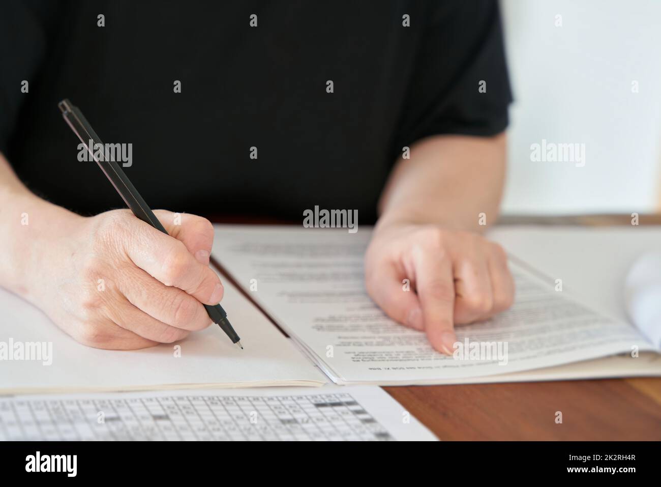 Close up of hand with pen writing at desk in office Stock Photo