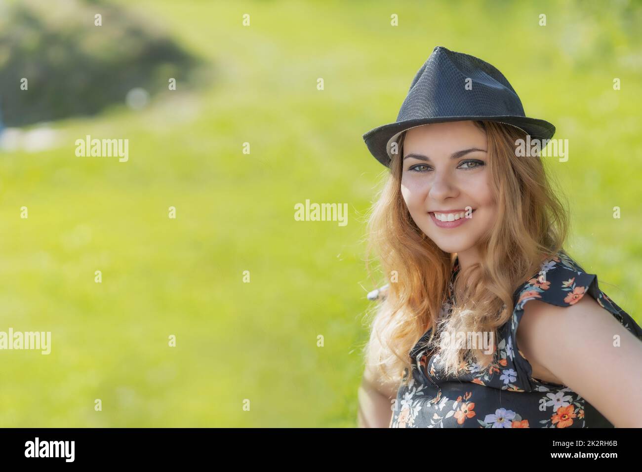 Portrait of attractive young woman in black straw hat posing outdoors ...