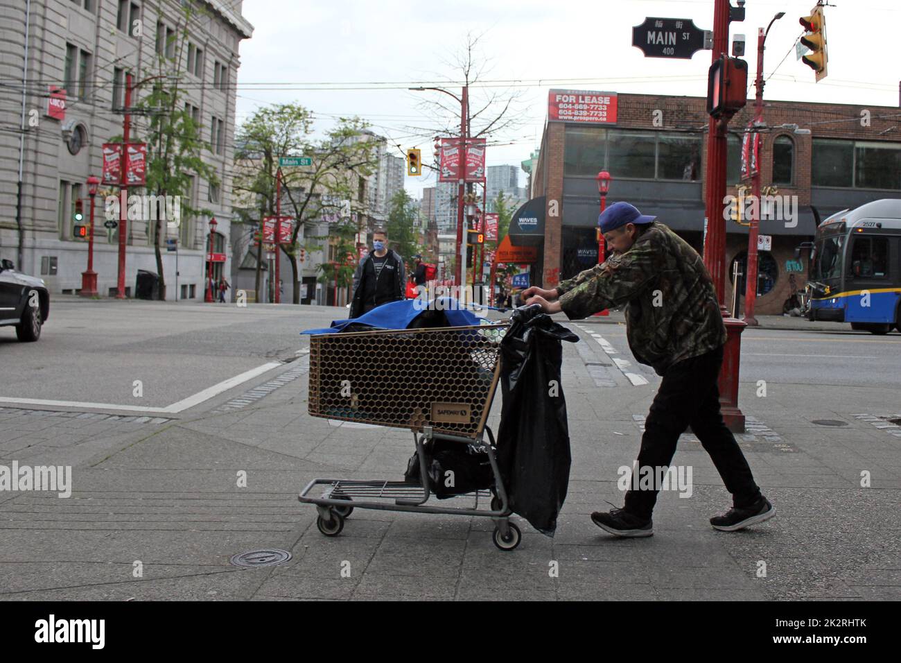 A homeless man pushing a shopping cart along the Main street in