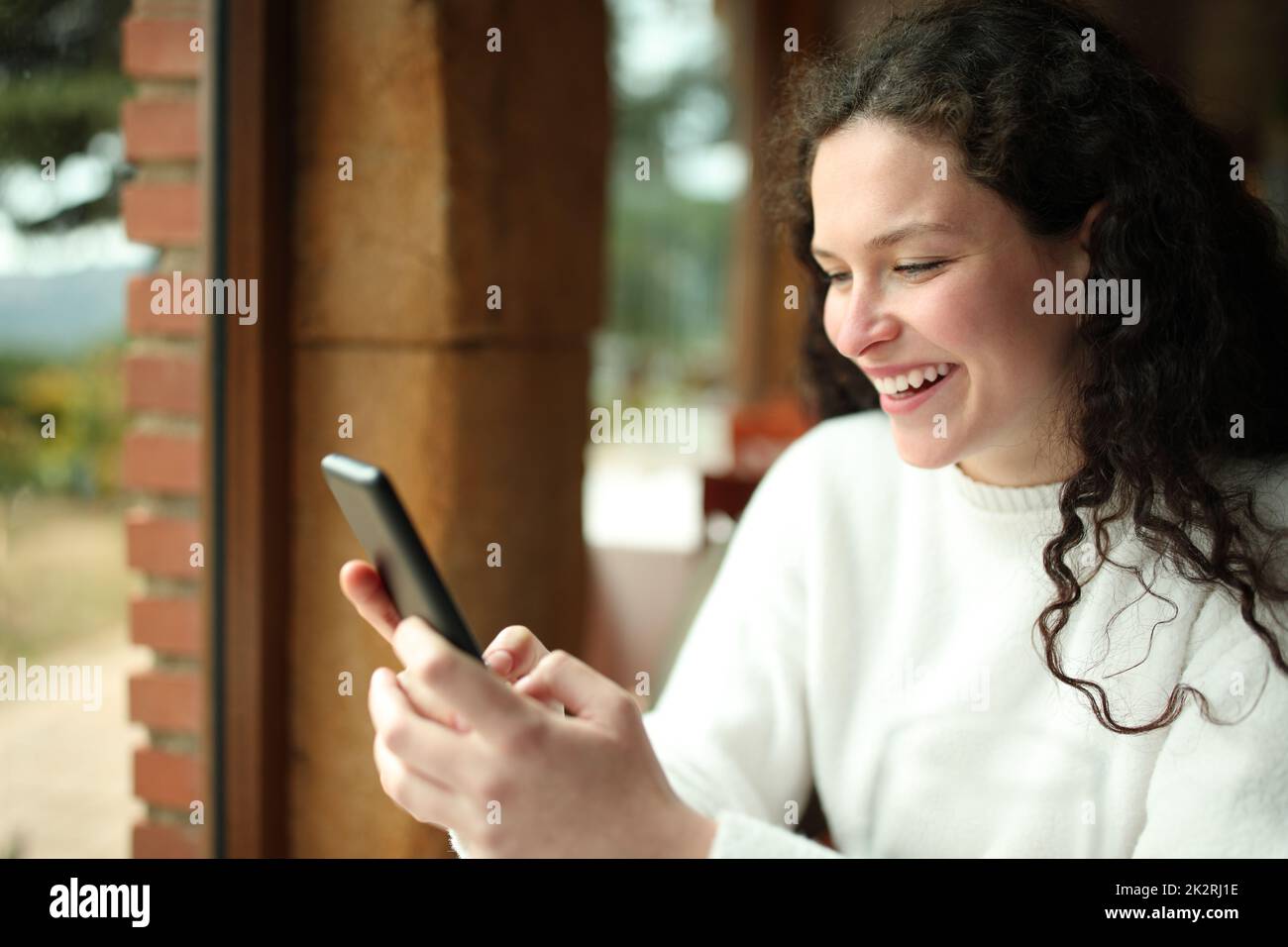 Happy woman checking smart phone in a restaurant Stock Photo