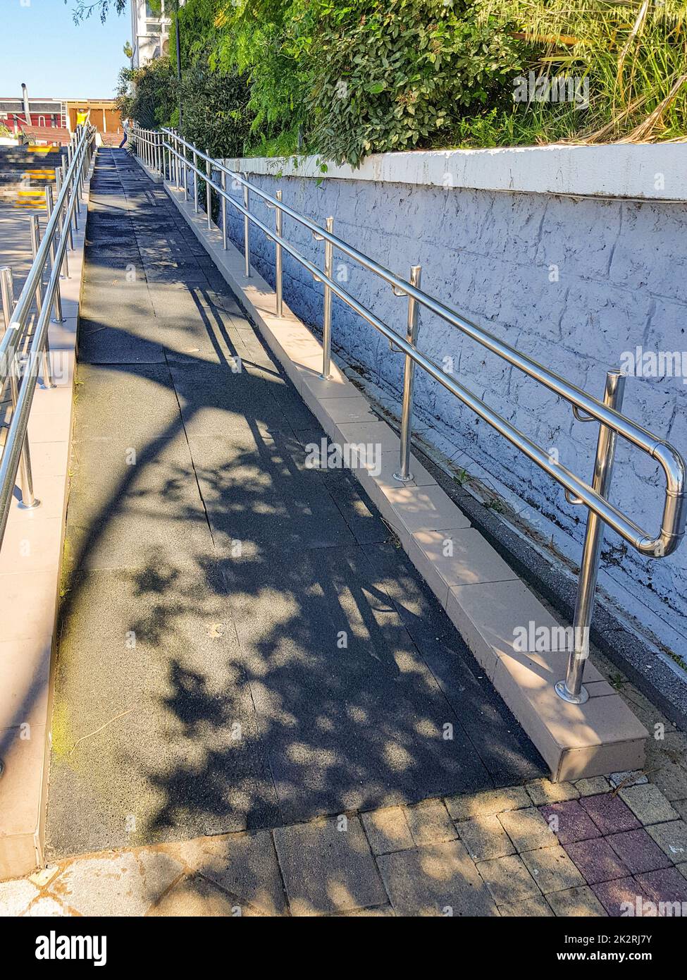 Modern ramp with shiny metal railings outdoors, wheelchair accessible, close-up, vertical Stock Photo