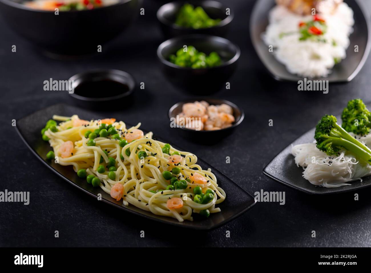 Various dishes of Asian cuisine with different types noodles and rice with shrimp, duck, vegetables and black sesame Stock Photo