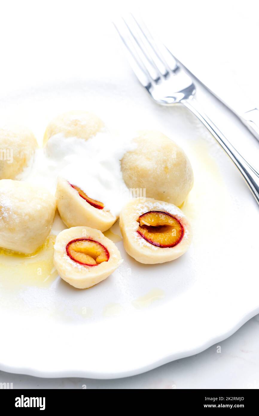 plum dumplings with sour cream, powder sugar and melted butter Stock