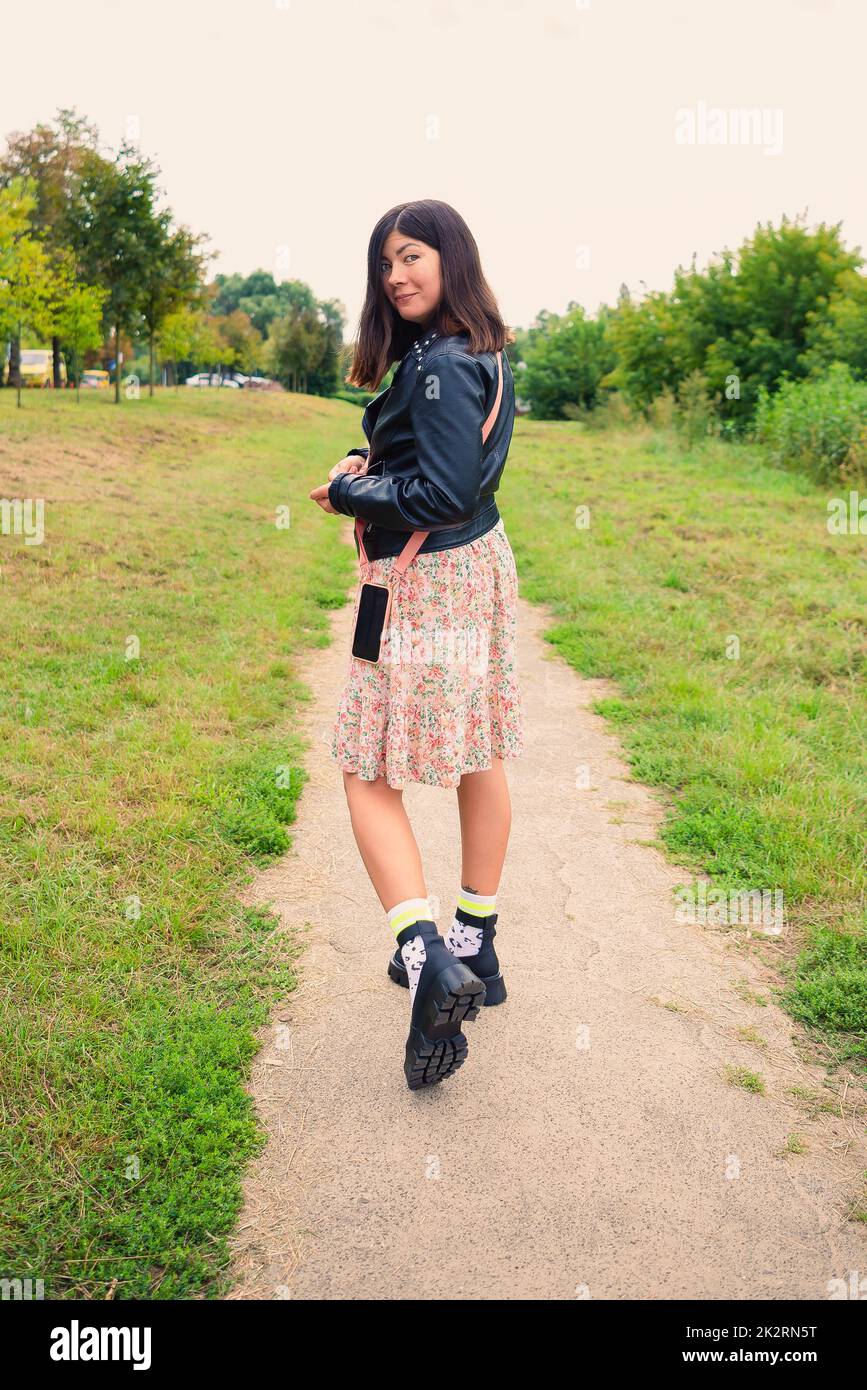 Full length portrait from the back of a young black-haired girl who is walking along a footpath Stock Photo