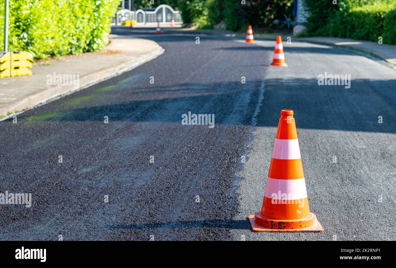 Construction cones marking part of road with a layer of fresh asphalt. Stock Photo
