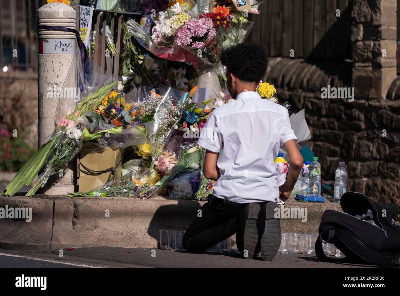 A pupil views floral tributes at the scene in Woodhouse Hill, Huddersfield, where 15-year-old schoolboy Khayri McLean was fatally stabbed outside his school gates. Picture date: Friday September 23, 2022. Stock Photo