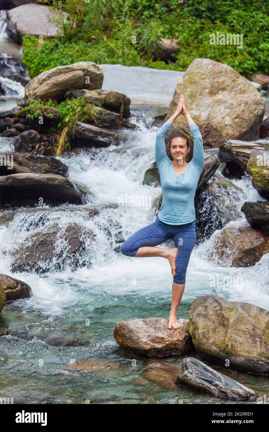 Woman in yoga asana Vrikshasana tree pose at waterfall outdoors Stock ...