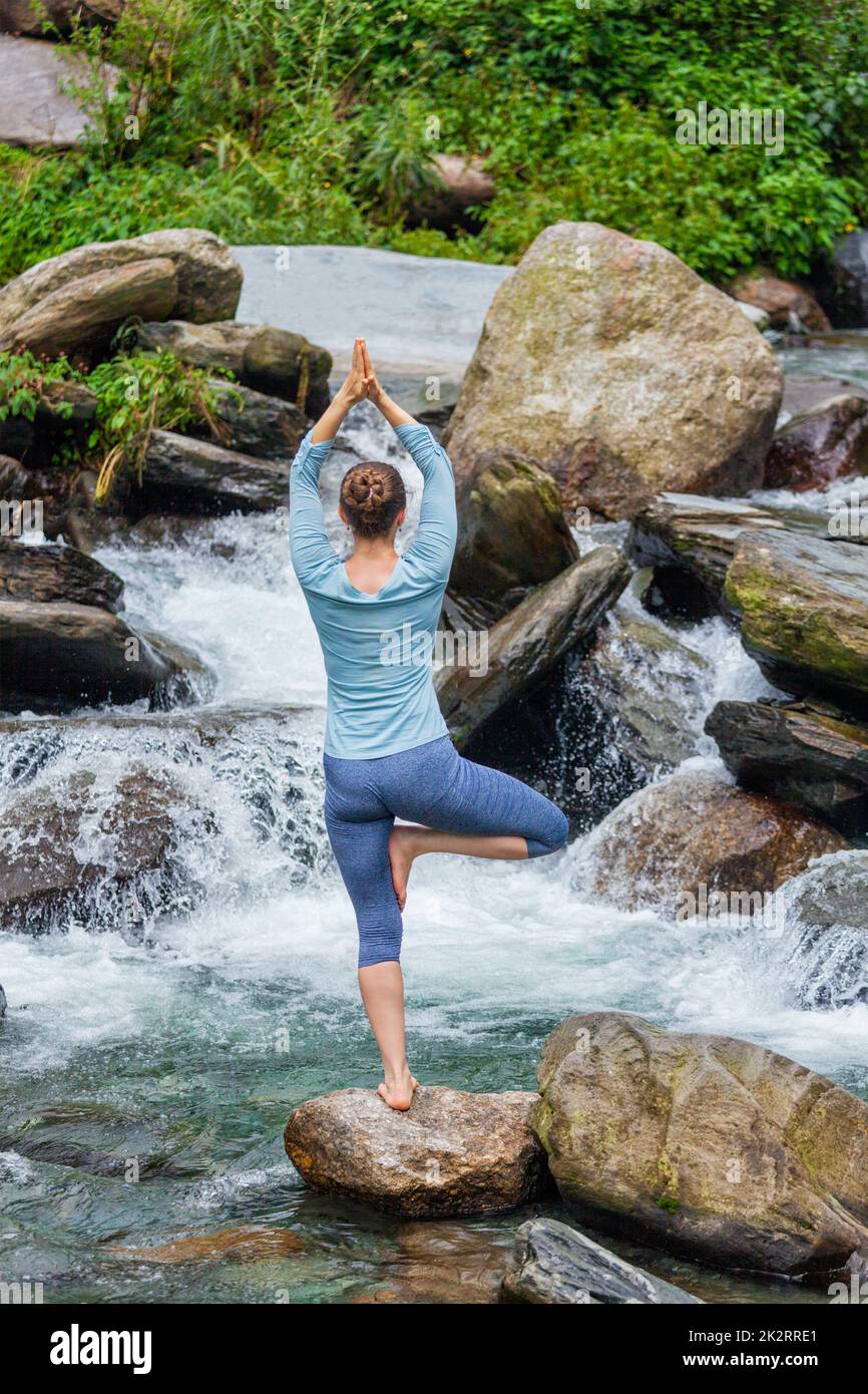 Woman in yoga asana Vrikshasana tree pose at waterfall outdoors Stock ...