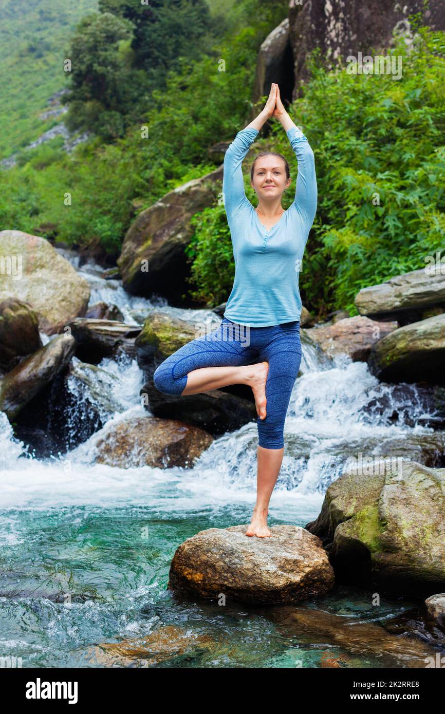 Woman in yoga asana Vrikshasana tree pose at waterfall outdoors Stock ...
