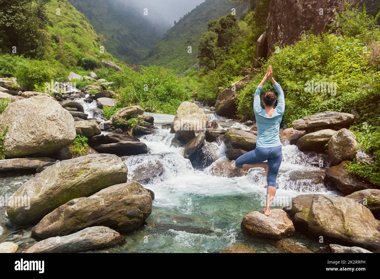 Woman in yoga asana Vrikshasana tree pose at waterfall outdoors Stock ...