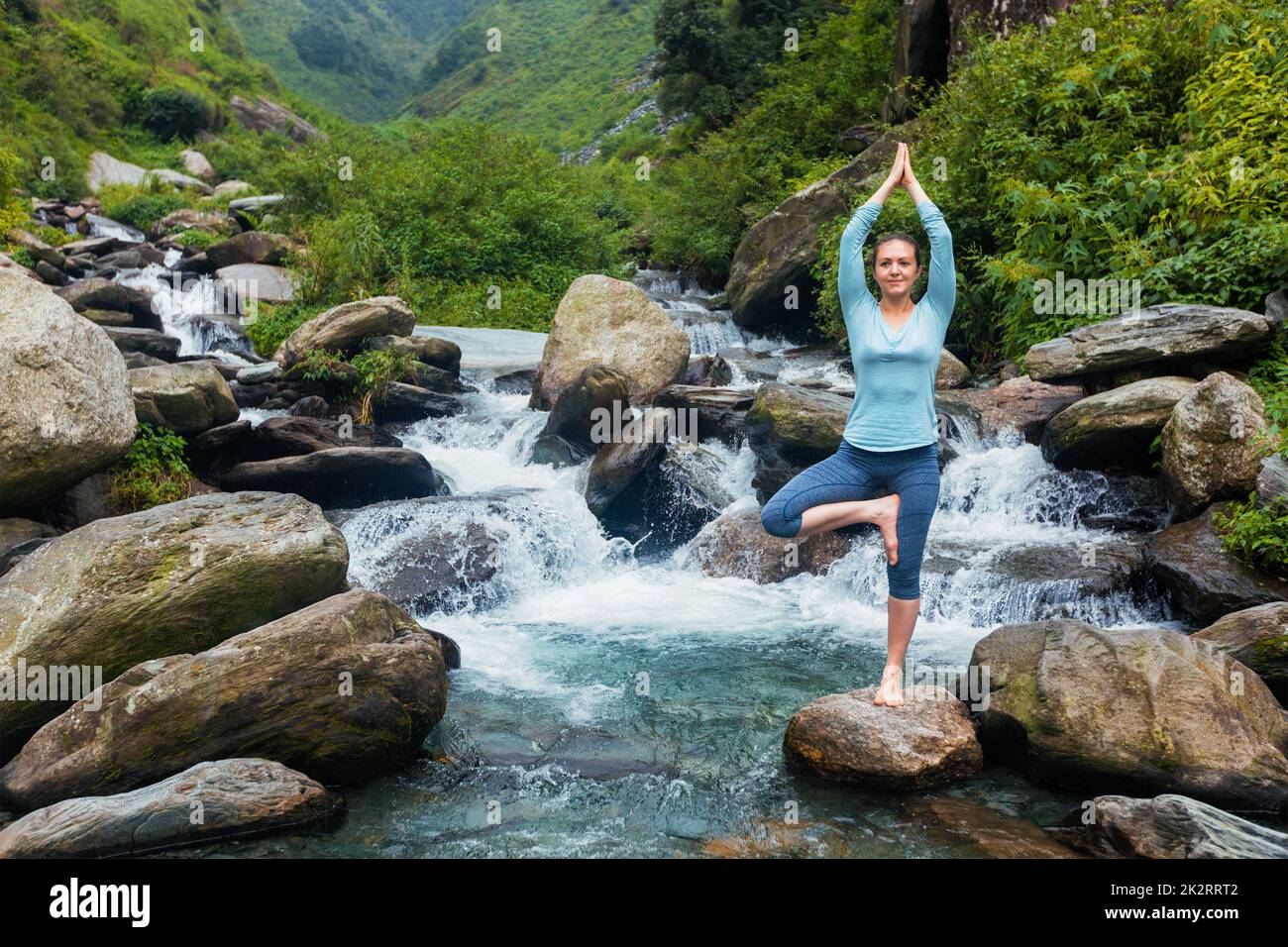 Woman in yoga asana Vrikshasana tree pose at waterfall outdoors Stock ...