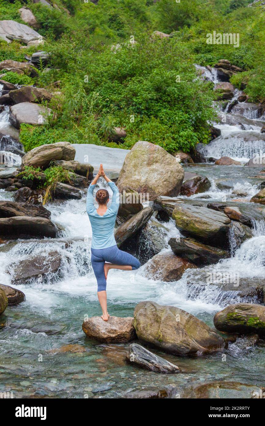 Woman in yoga asana Vrikshasana tree pose at waterfall outdoors Stock ...
