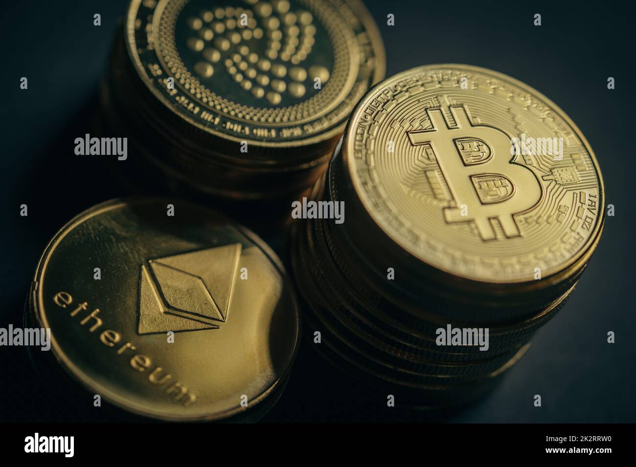 Close up shot of stacks of golden Bitcoin, IOTA and Ethereum digital cryptocurrency coins. Stock Photo