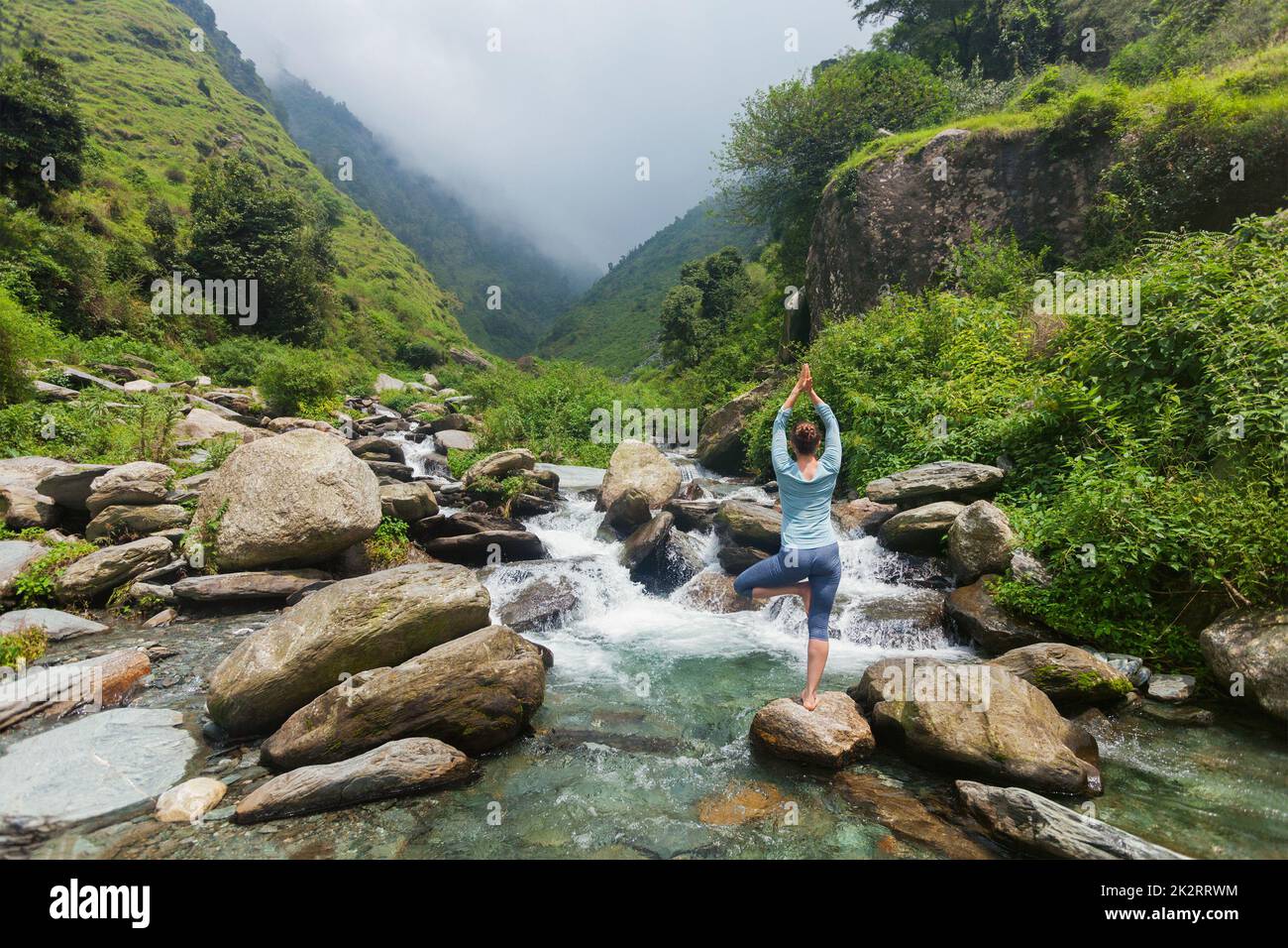 Woman in yoga asana Vrikshasana tree pose at waterfall outdoors Stock ...