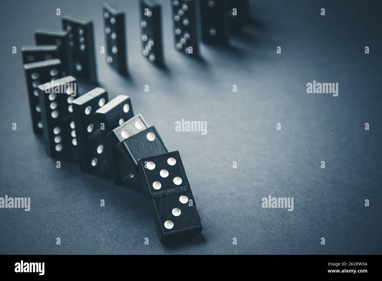 Black dominoes chain on dark table background Stock Photo