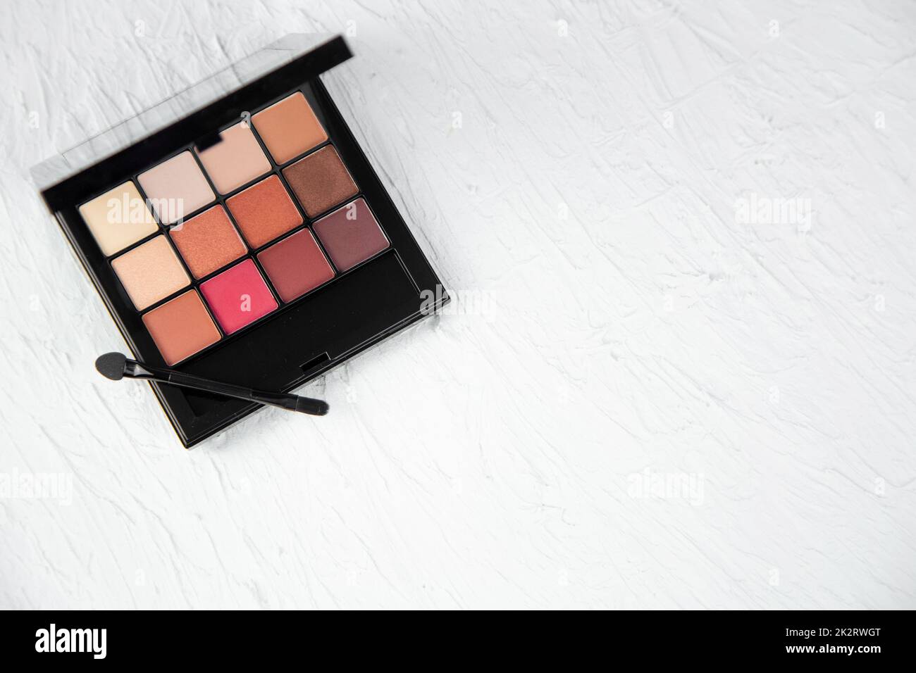The eyeshadow palette lies in the upper left corner on a white textured background Stock Photo