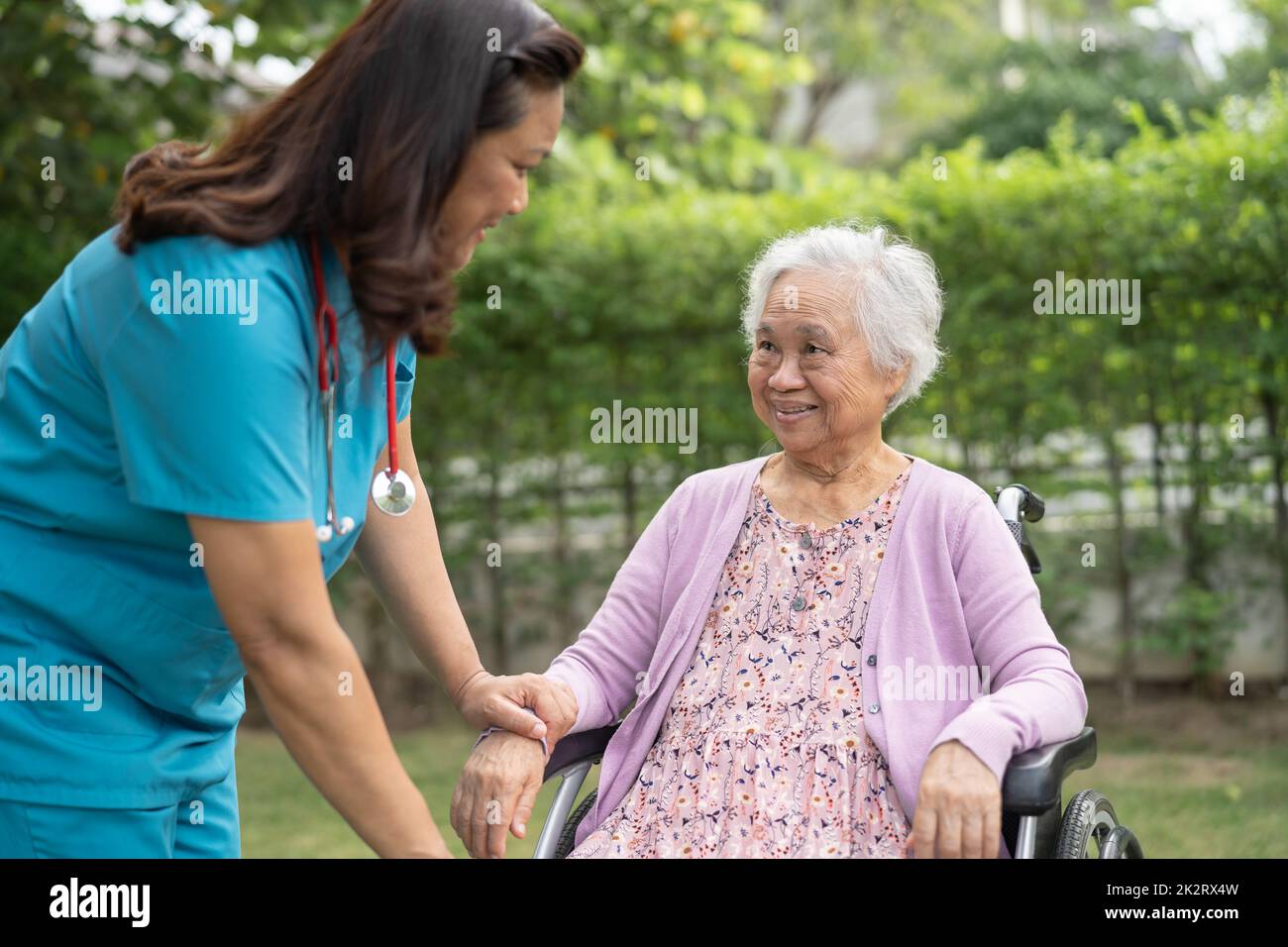 Doctor caregiver help and care Asian senior or elderly old lady woman patient sitting on wheelchair in park at nursing hospital, healthy strong medical concept Stock Photo