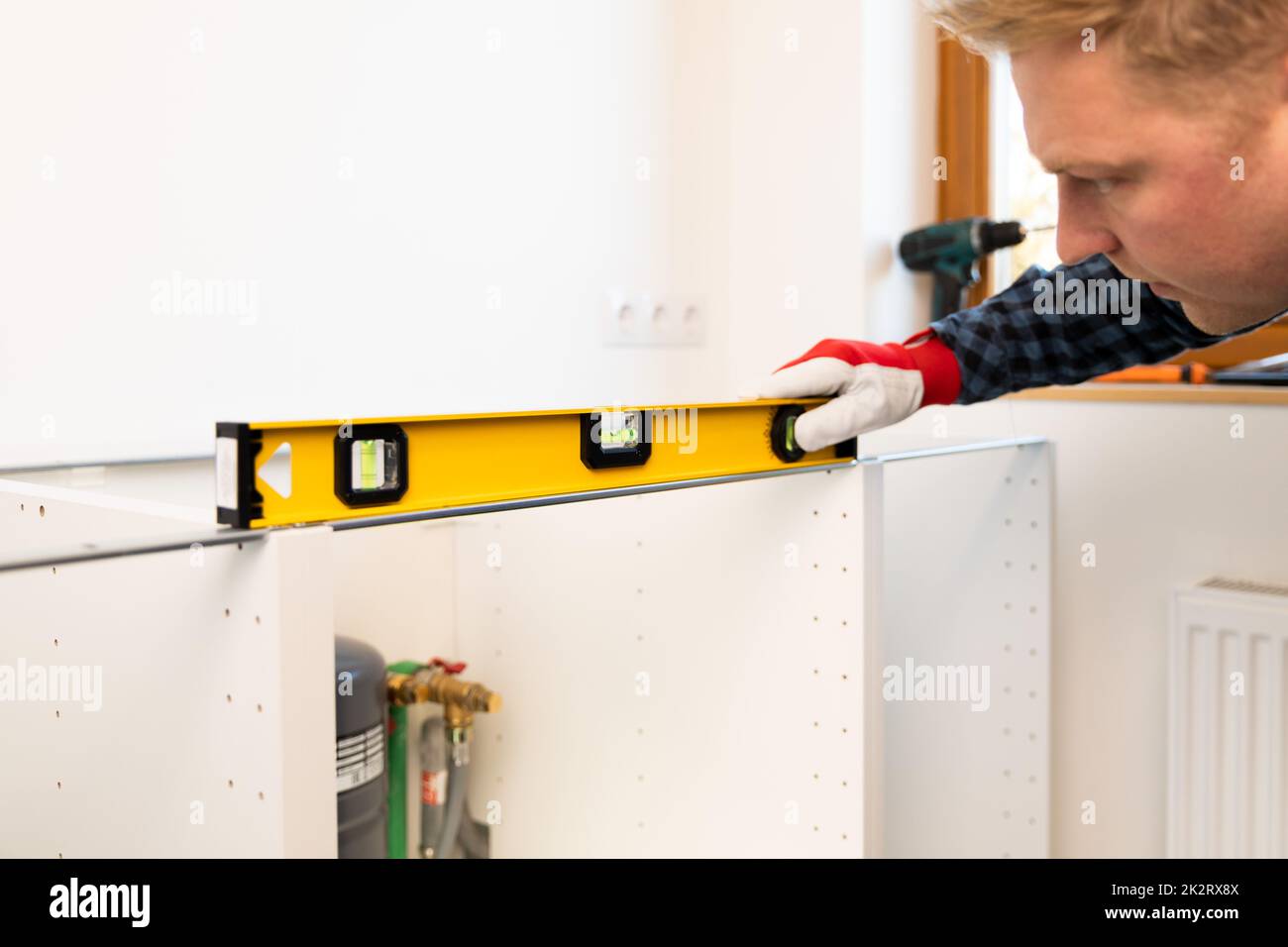 Home improvement. Handyman with leveler install new countertop in newly renovated kitchen. Stock Photo