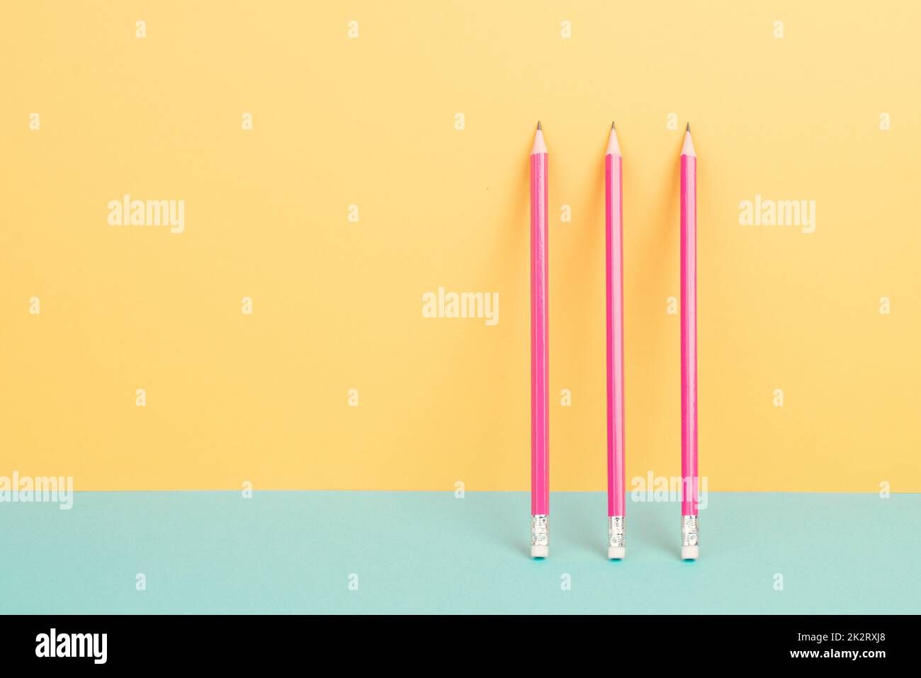 Pink pencils on a yellow and blue background, minimalism, creative, surreal and education concept, copy space for text, pastel colored wall Stock Photo
