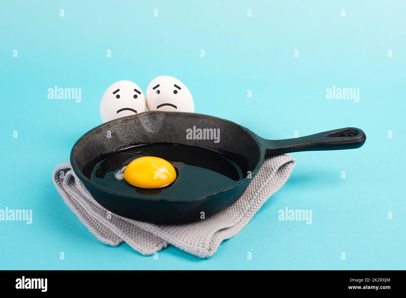 A fried egg in a pan, two friends look with sad faces at him, having a breakfast in the morning, funny food, broken friendship, healthy food Stock Photo