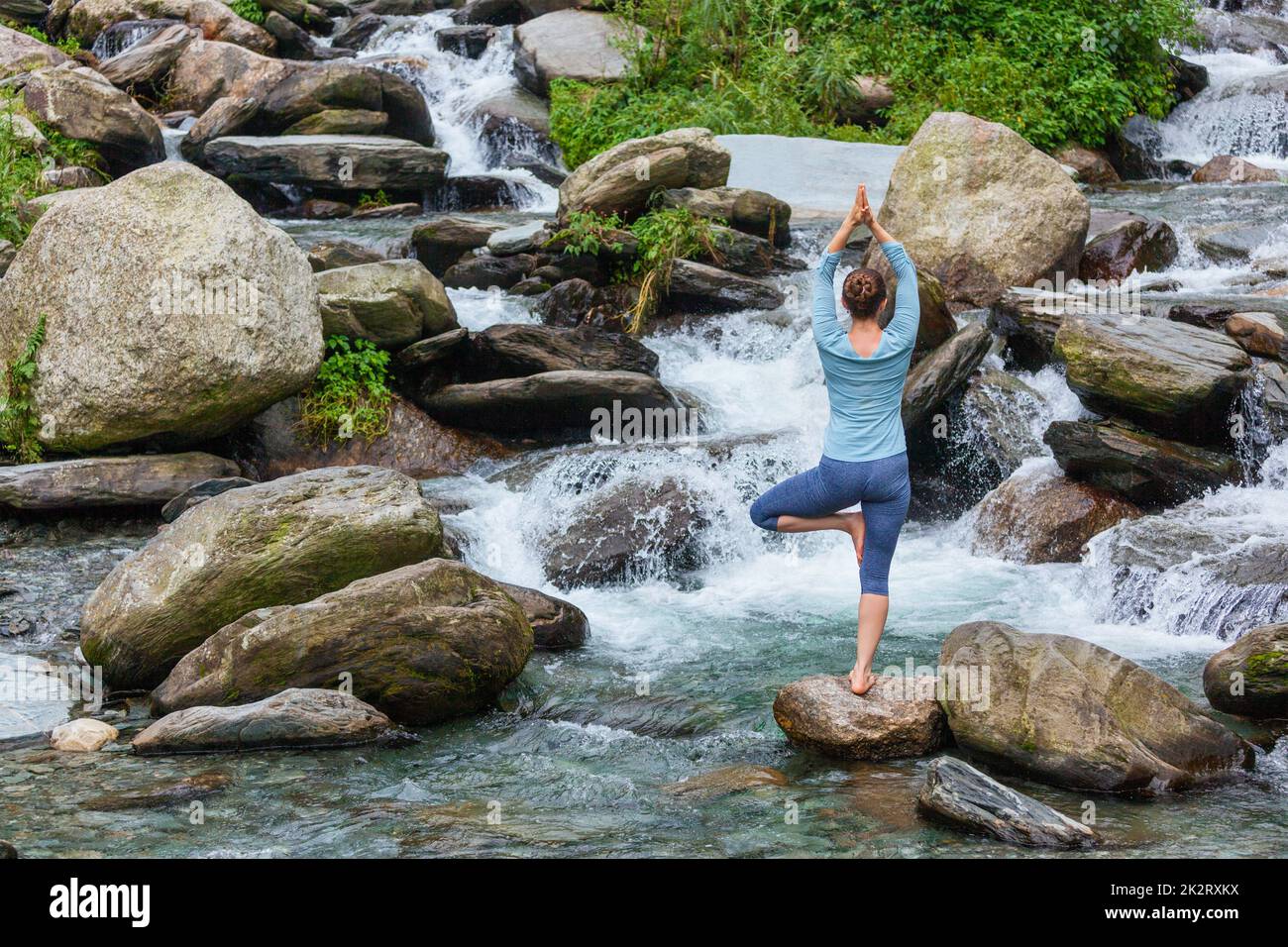 Woman in yoga asana Vrikshasana tree pose at waterfall outdoors Stock ...