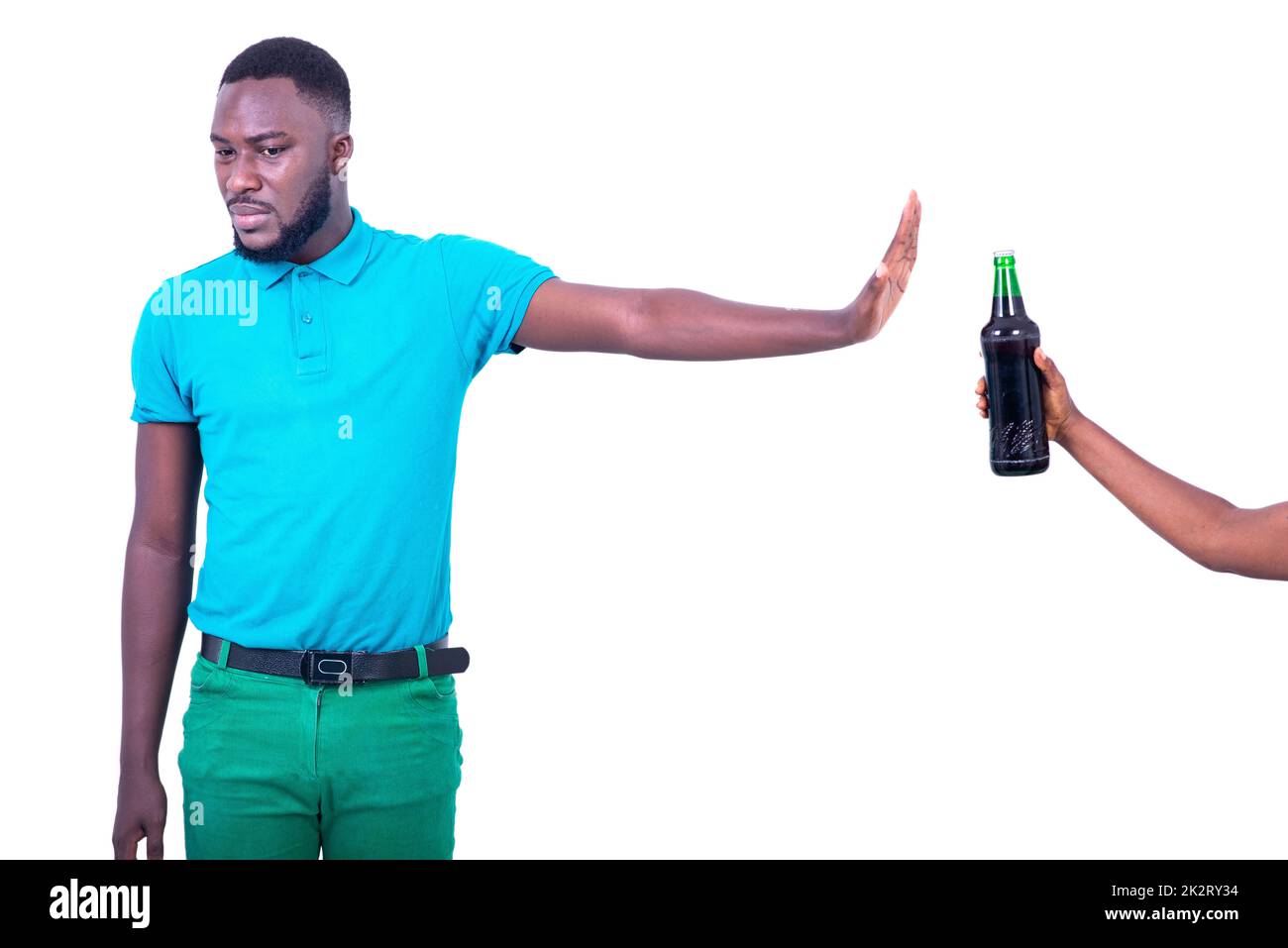 portrait of the handsome young man wearing a blue t-shirt, refusing the bottle of beer. Stock Photo