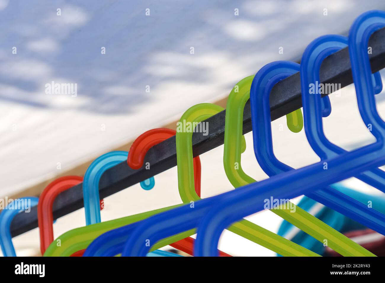 Numerous colourful plastic clothes hangers on a clothes rail Stock