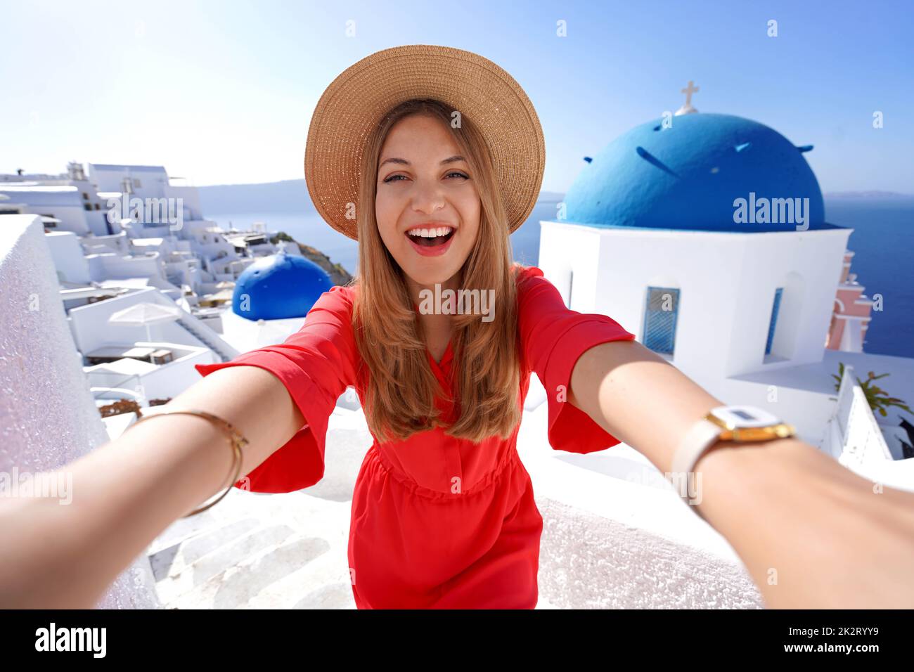 Excited traveler girl taking selfie photo in Oia picturesque greek village of Santorini Island. Young woman having fun in Greece, Europe. Stock Photo