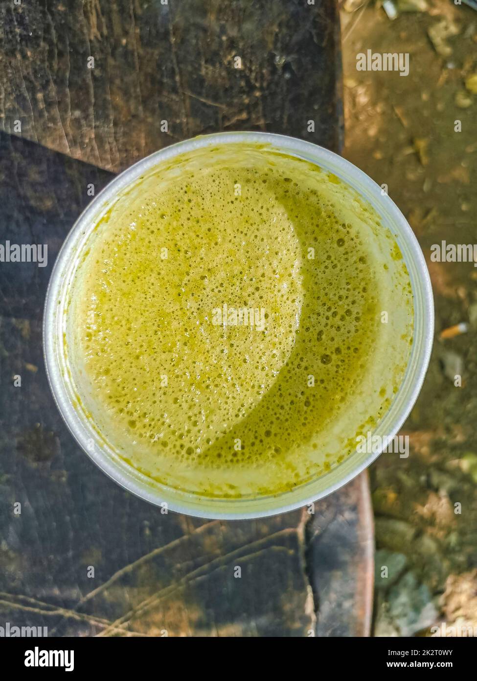 Green smoothie juice on bench in a park wooden background. Stock Photo