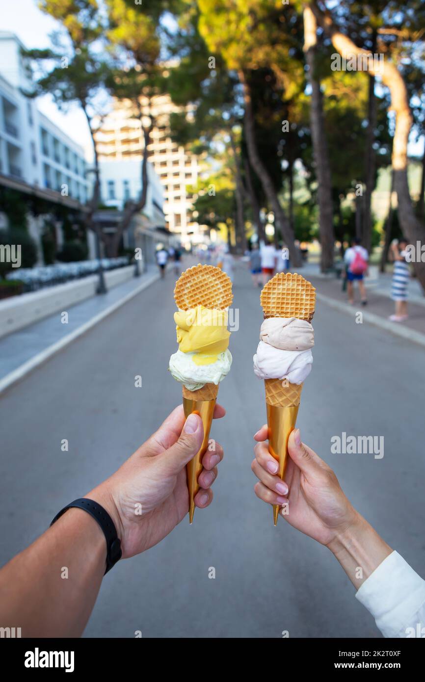 Saint Stephen, Montenegro, 07.07.2021: Beautiful bright ice cream with different flavors in the hands of a young couple in love. Beautiful city streets. Leisure concept. Stock Photo