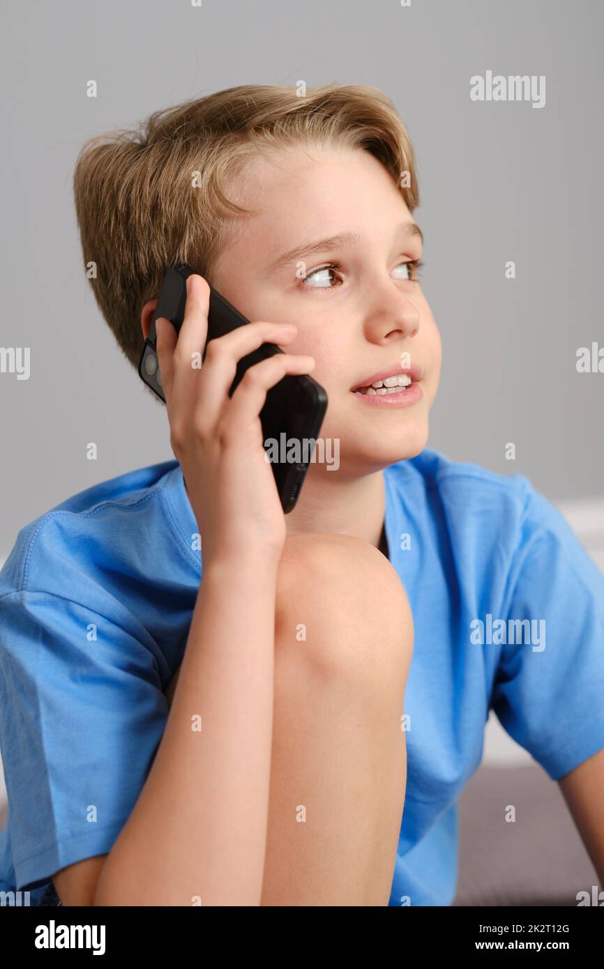 Generation Z boy talking on the phone at home. Portrait of a cute happy child. Stock Photo