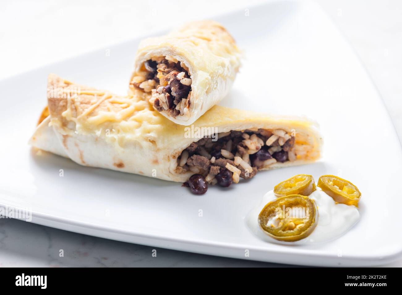 beef burrito with rice and beans served with whipped cream and jalapenos Stock Photo