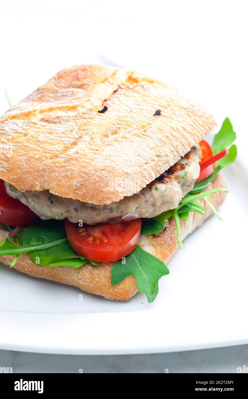 homemade turkey burger with cherry tomatoes and arugula in ciabatta