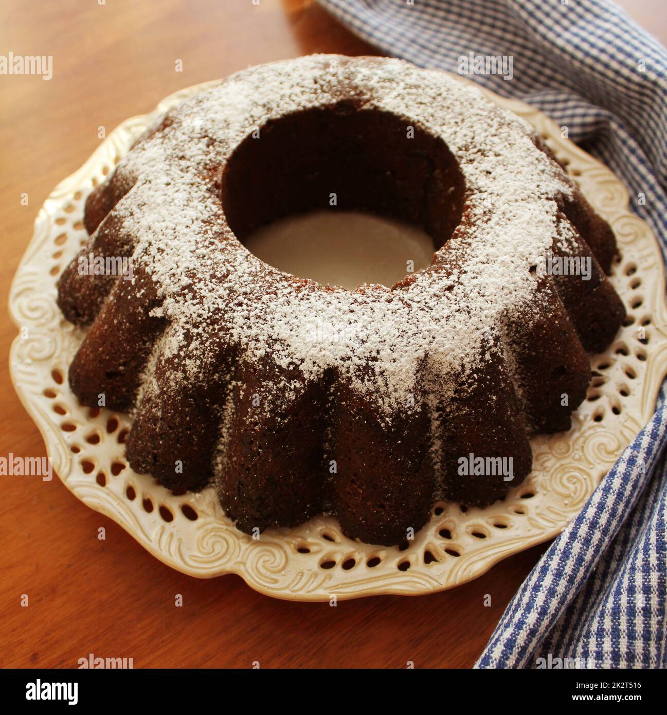 Chocolate bunt cake sprinkled with sugar powder on a plate white background Stock Photo