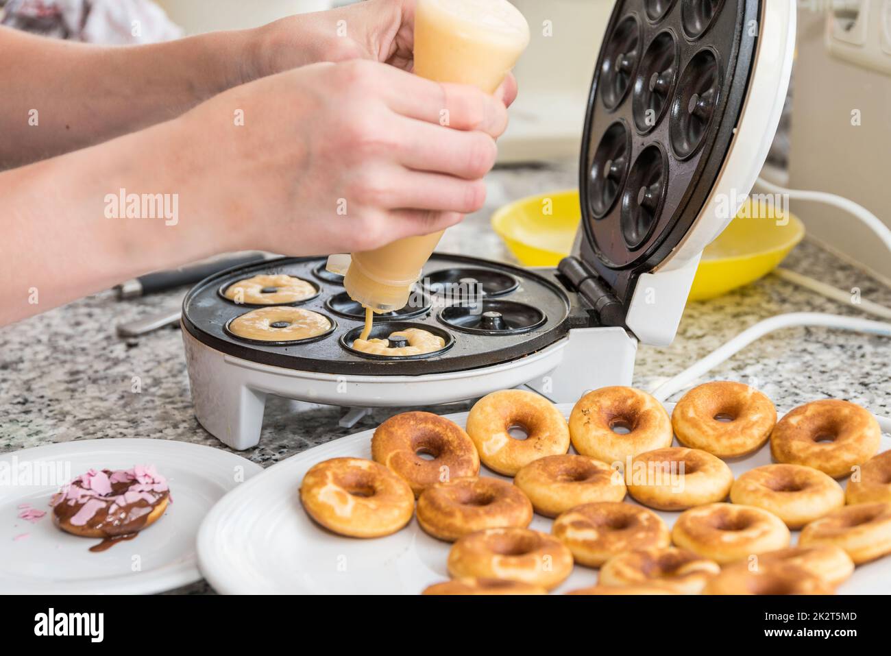 prepare delicious little donuts with donut machine - bake dessert Stock Photo