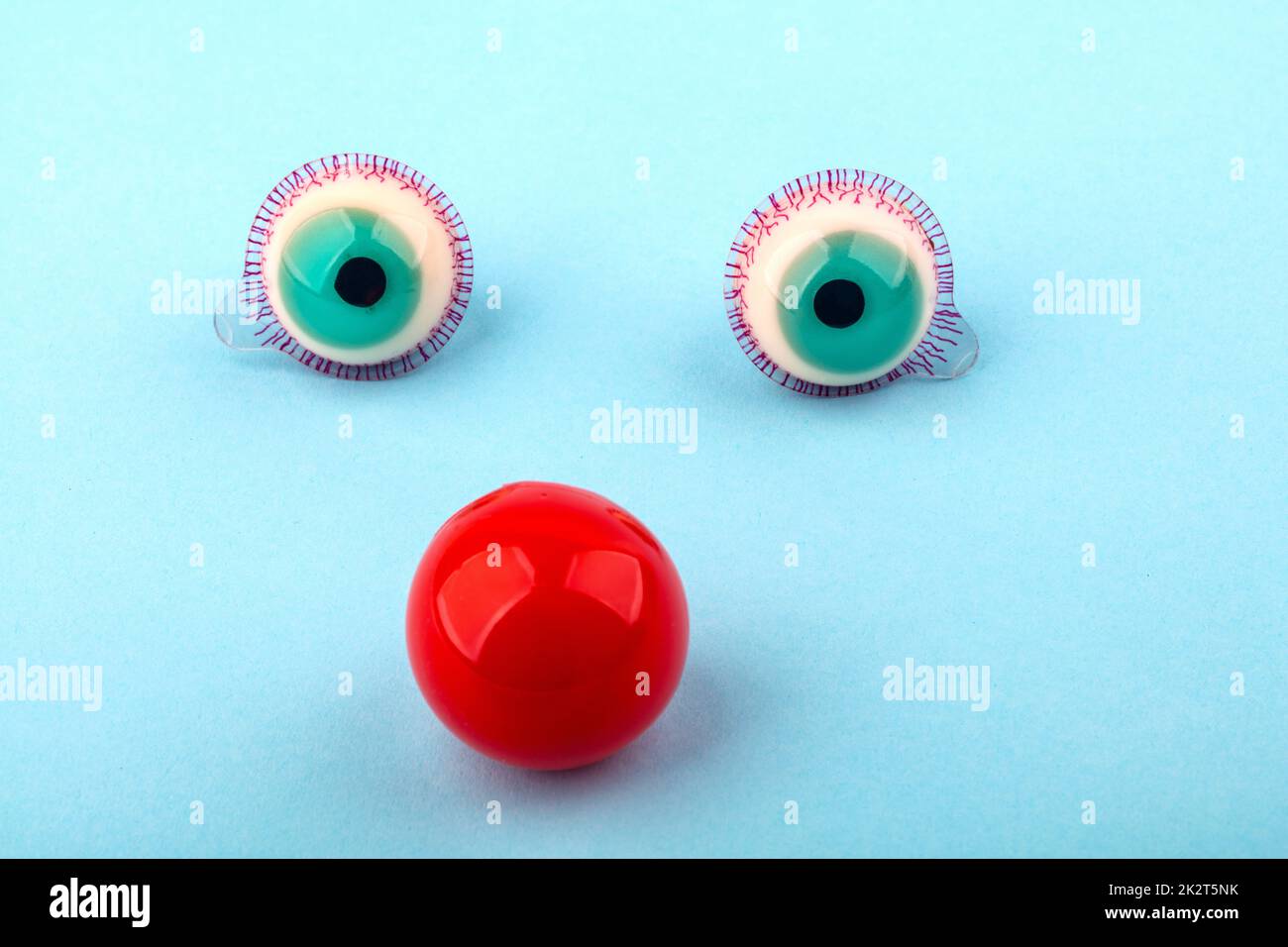 Decorative fruit candy eyes with red nose over light blue background. Conceptual photo using for funny celebration themes. Stock Photo