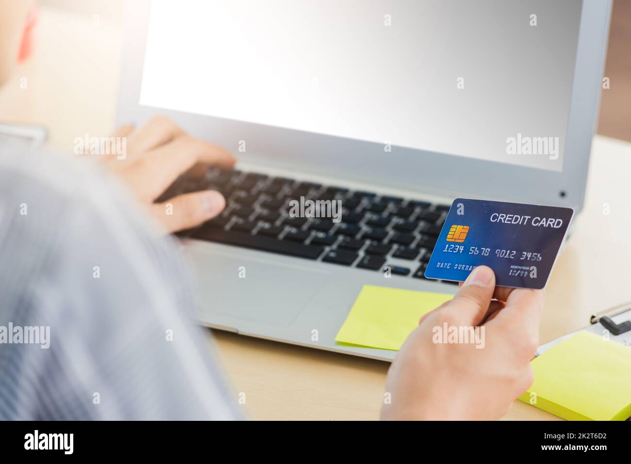 business man hand holding credit card and typing entering security code on a laptop computer Stock Photo