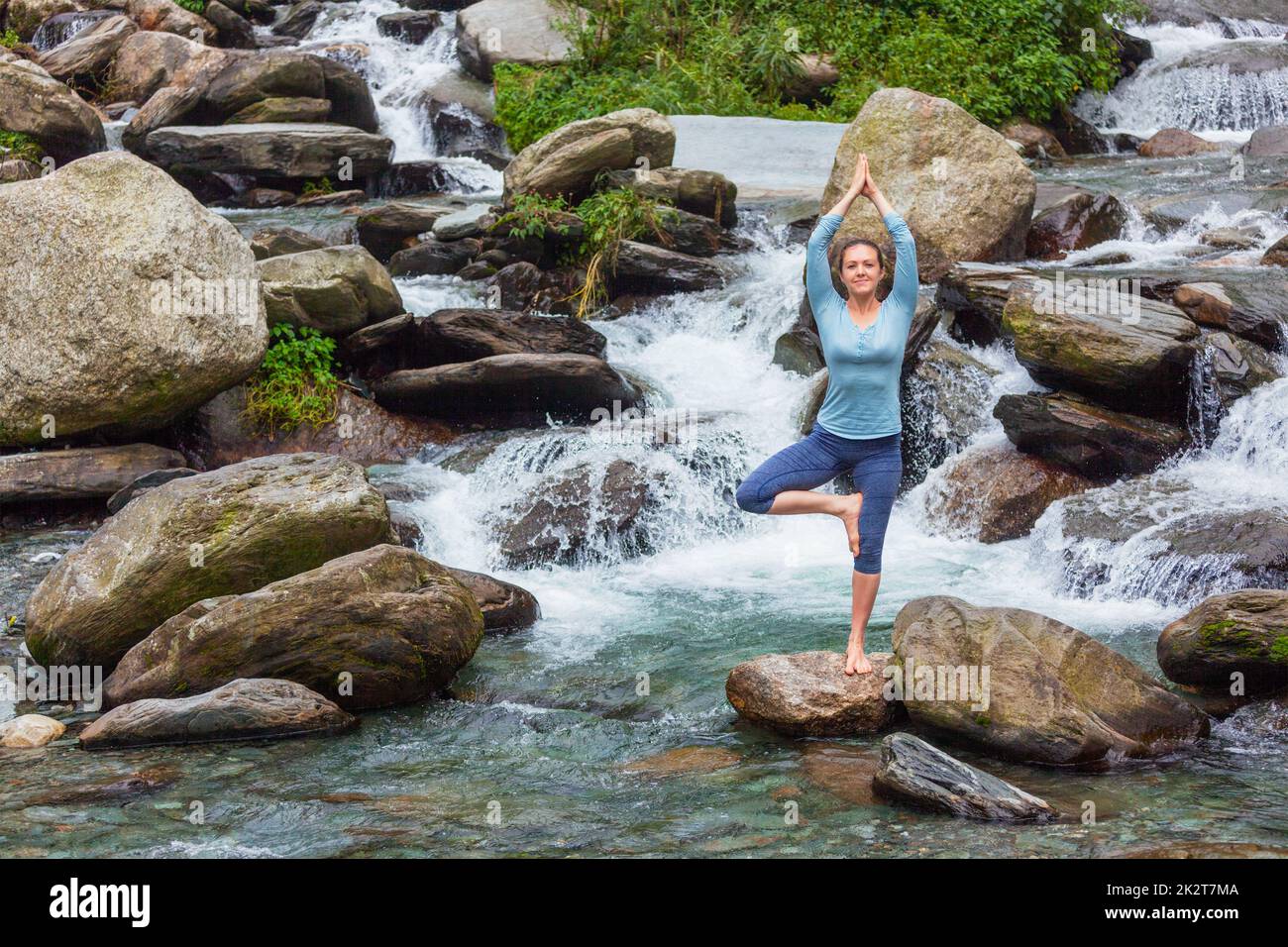 Woman in yoga asana Vrikshasana tree pose at waterfall outdoors Stock ...