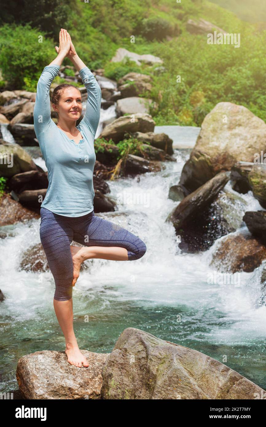 Woman in yoga asana Vrikshasana tree pose at waterfall outdoors Stock ...